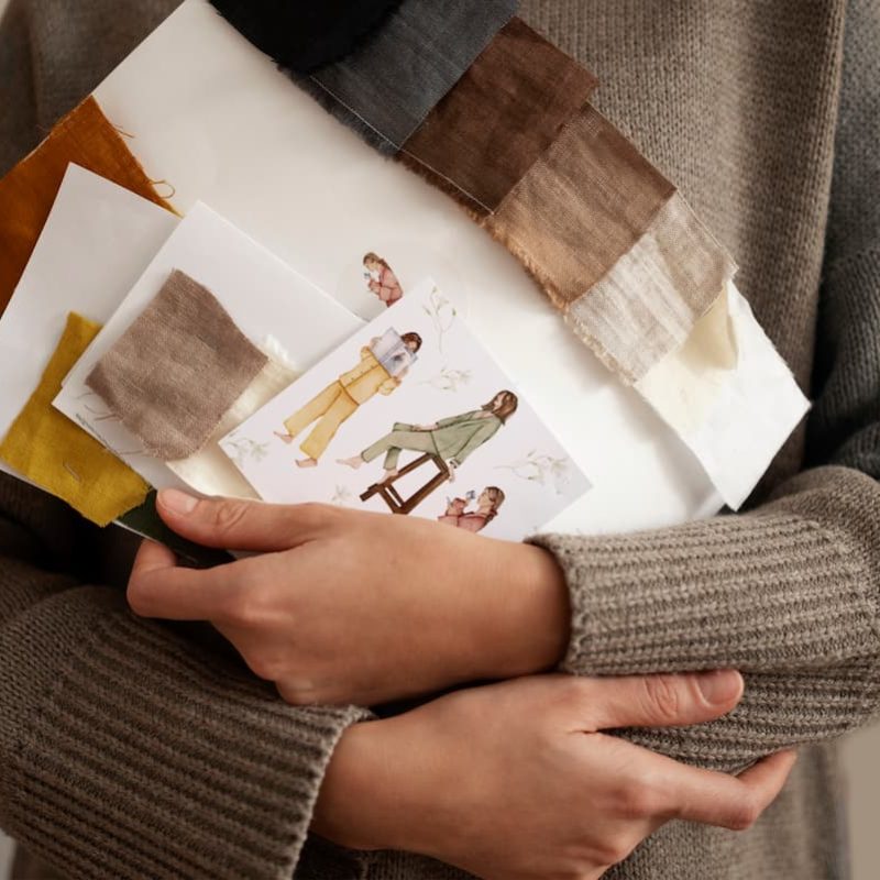 Frau hält Muster und Designideen in der Hand und stellt damit eine Konzepterstellung dar