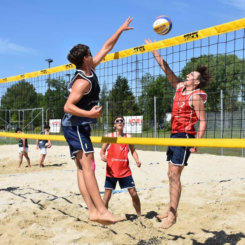 Drei junge Männer beim Beachvolleyball spielen in funktionaler Sportbekleidung